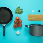 Kitchen Utensils - flat lay photography of frying pan beside tomatoes on blue surface